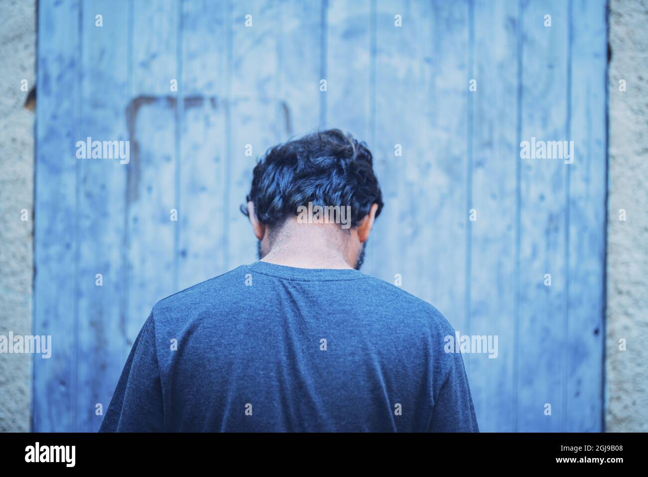 Uomo che torna alla fotocamera sensazione da solo. Vista posteriore dell'uomo pensieroso che si sente solo o triste. Indietro di uomo dispiaciuto in profondo pensiero con faccia in giù dentro Foto Stock