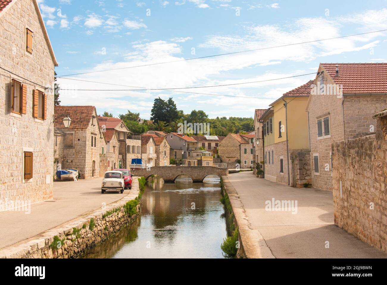 Croazia, isola di Hvar, Vrboska. Conosciuta come la piccola Venezia per i suoi canali e ponti, le piccole auto europee si adattano meglio alle strette corsie. Foto Stock