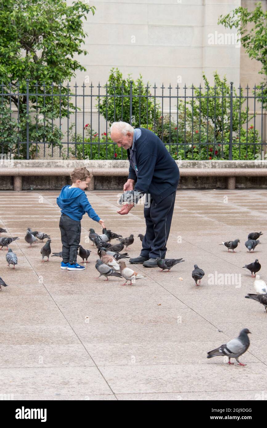 Europa, Croazia, Zagabria. L'uomo insegna ai bambini come nutrire i piccioni in Piazza Petra Preradovica Foto Stock