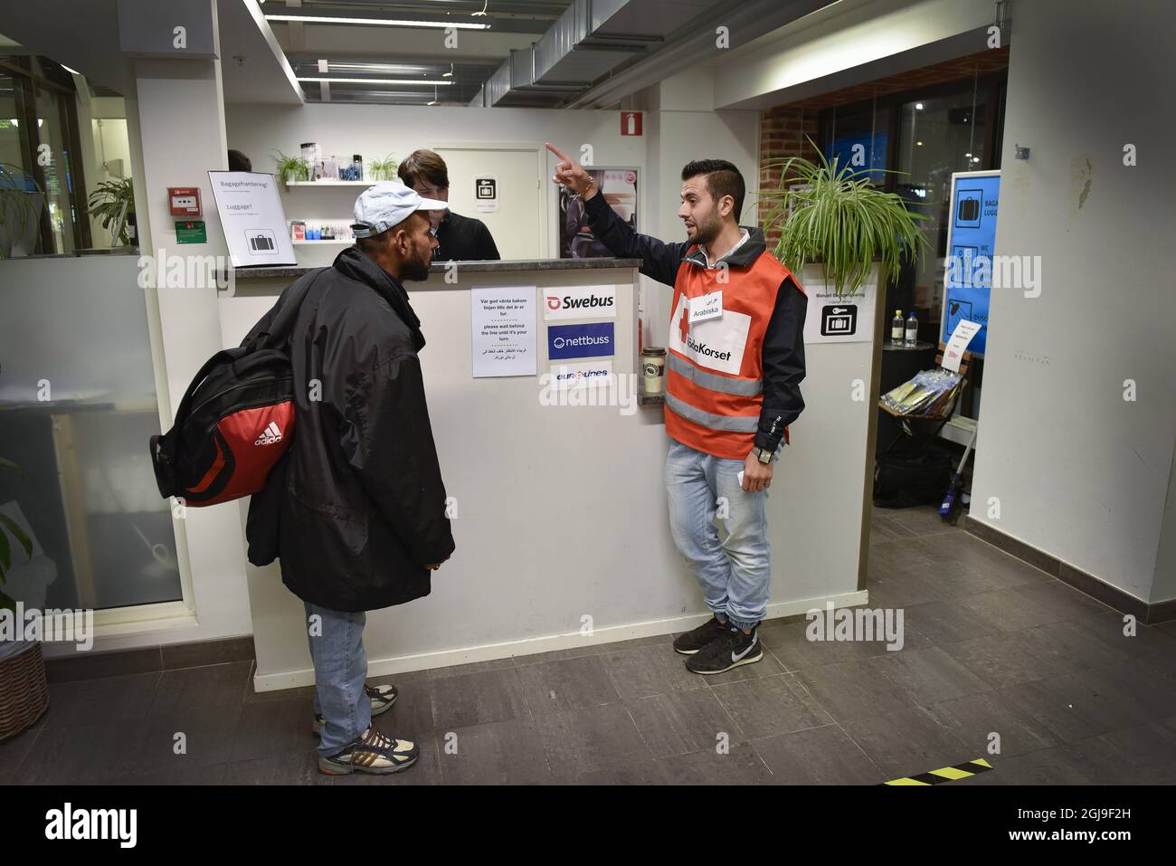 STOCCOLMA 2015-10-08 Foto data 20150928 il volontario della Croce Rossa Wael al Mubarakm stesso un rifugiato dalla Siria, è visto aiutare un nuovo rifugiato arrivato con un biglietto di autobus per Oslo alla stazione ferroviaria di Malmo, Svezia, 28 settembre 2015. Foto: Anders Wiklund / TT / Kod 10040 Foto Stock