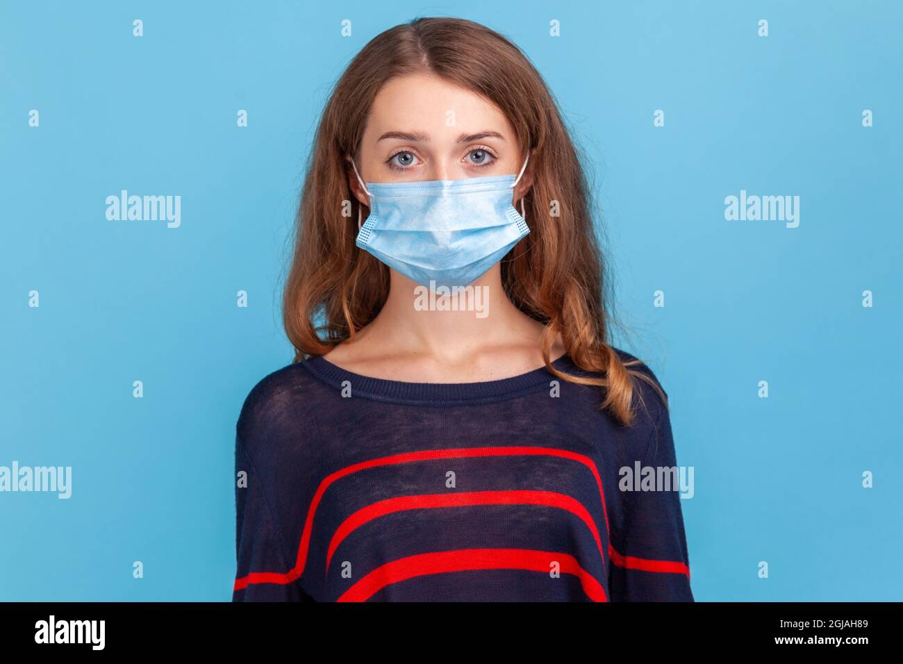 Donna seria indossando a strisce stile casual maglione e maschera medica prevenire l'infezione, malattie respiratorie aeree come l'influenza, Covid-2019. St. Al coperto Foto Stock
