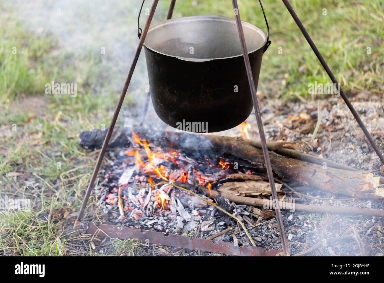 Pot turistico appesa sopra il fuoco su un treppiede. La cucina in campagna. Foto Stock
