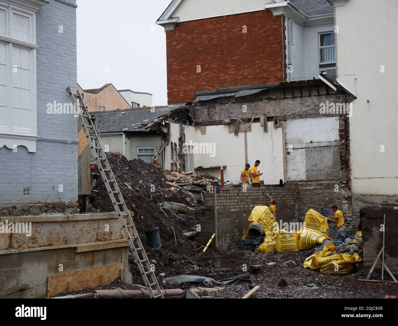 Costruttori che lavorano su una parete di contenimento del blocco al confine di un cantiere. Plymouth, Devon, Regno Unito. Foto Stock