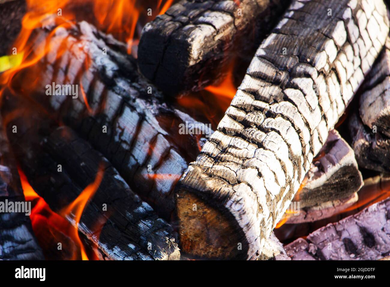 Un log di masterizzazione di un albero in primo piano come sfondo astratto. I carboni caldi di un camino che brucia il legno Foto Stock