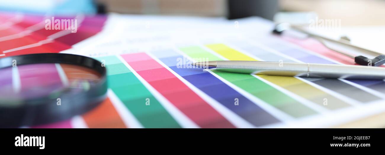 La tavolozza dei colori con penna e lente di ingrandimento è sul tavolo Foto Stock