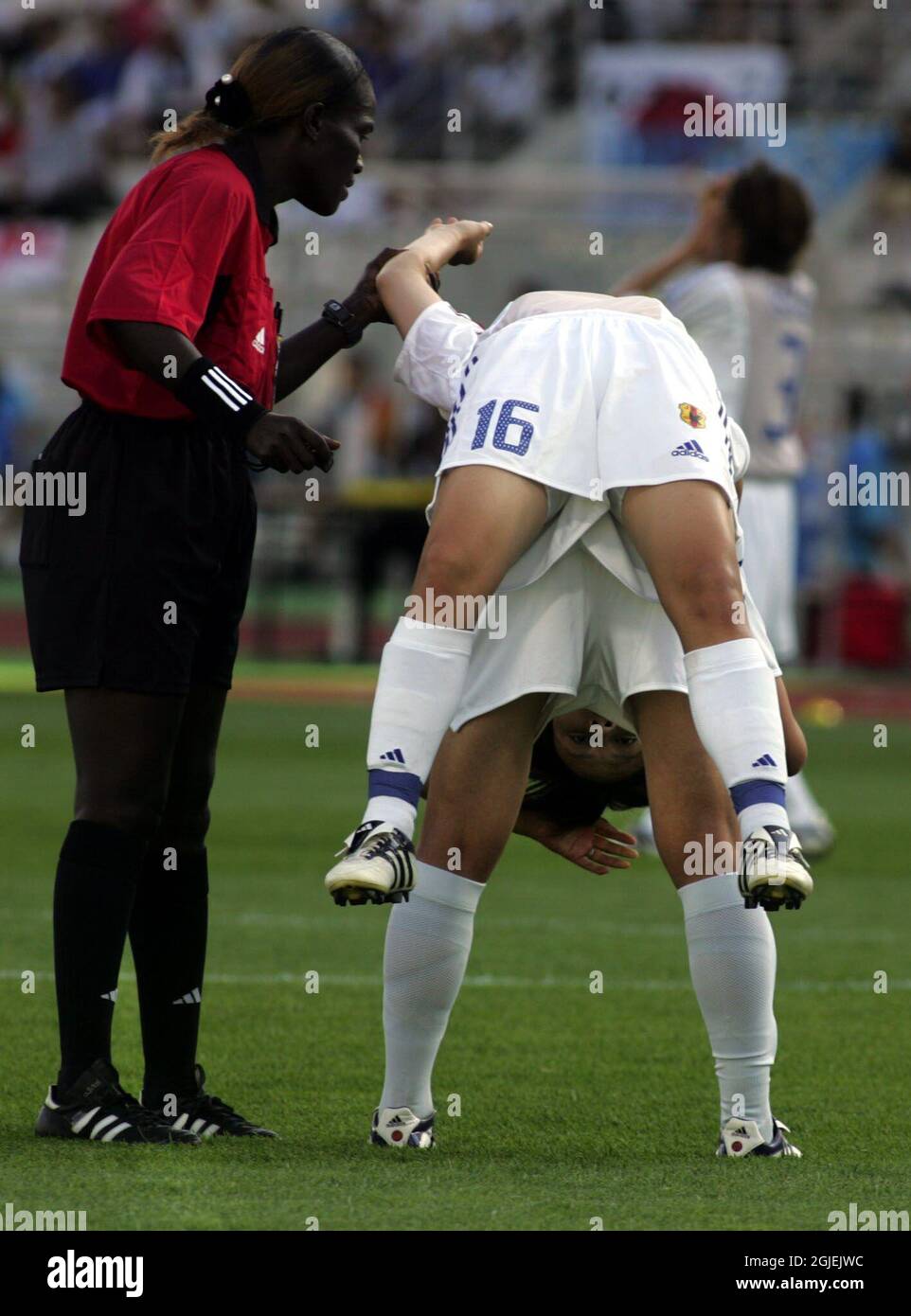 L'arbitro Fatou Gaye (l) si trova accanto allo Yayoi Kobayashi (top) del Giappone mentre si stende in cima a un compagno di squadra. Foto Stock