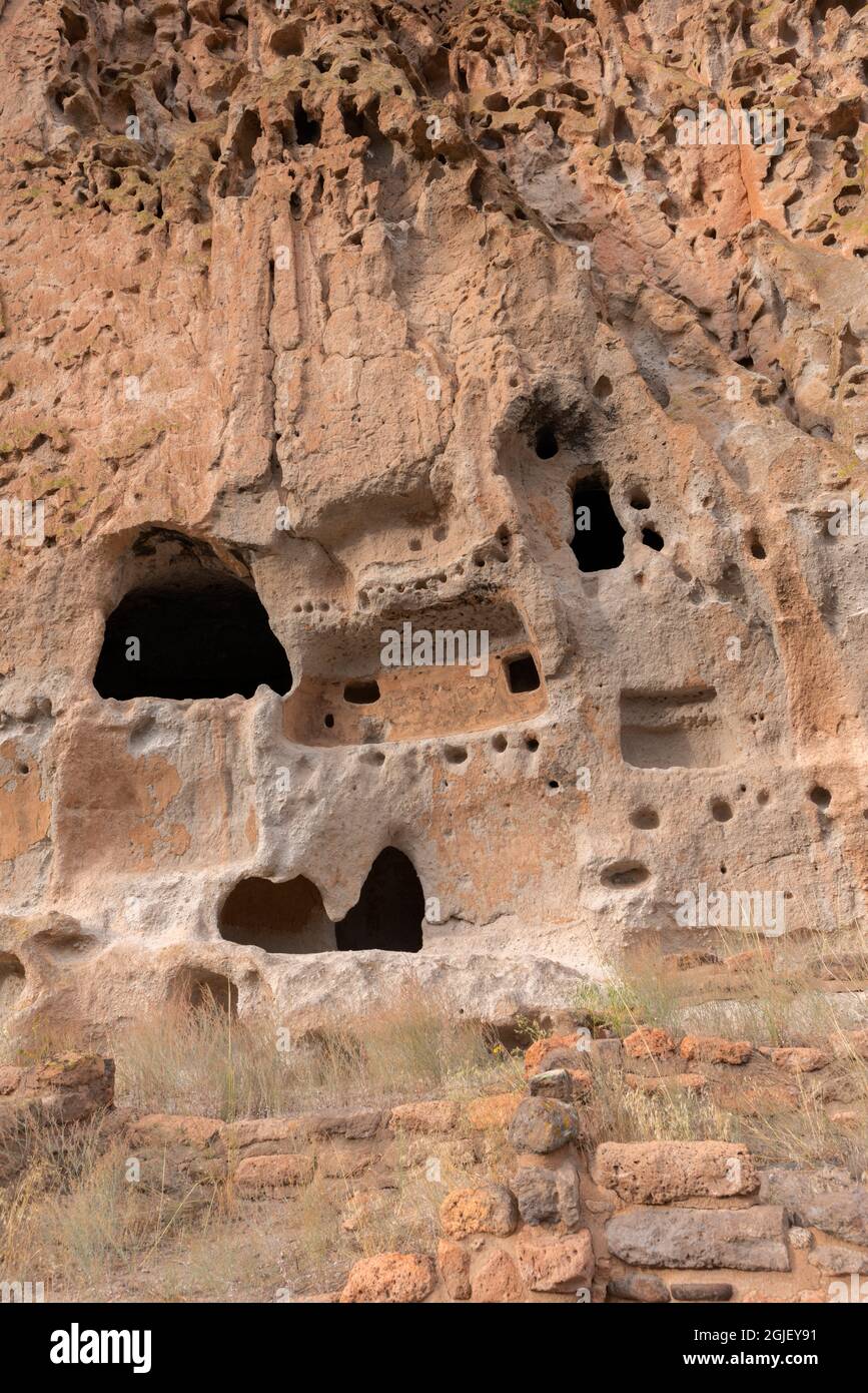 USA, New Mexico. Bandelier National Monument, rovine di pietra sotto le entrate di abitazioni scavate in morbida roccia vulcanica chiamata tufo nel Frijoles Canyon. Foto Stock