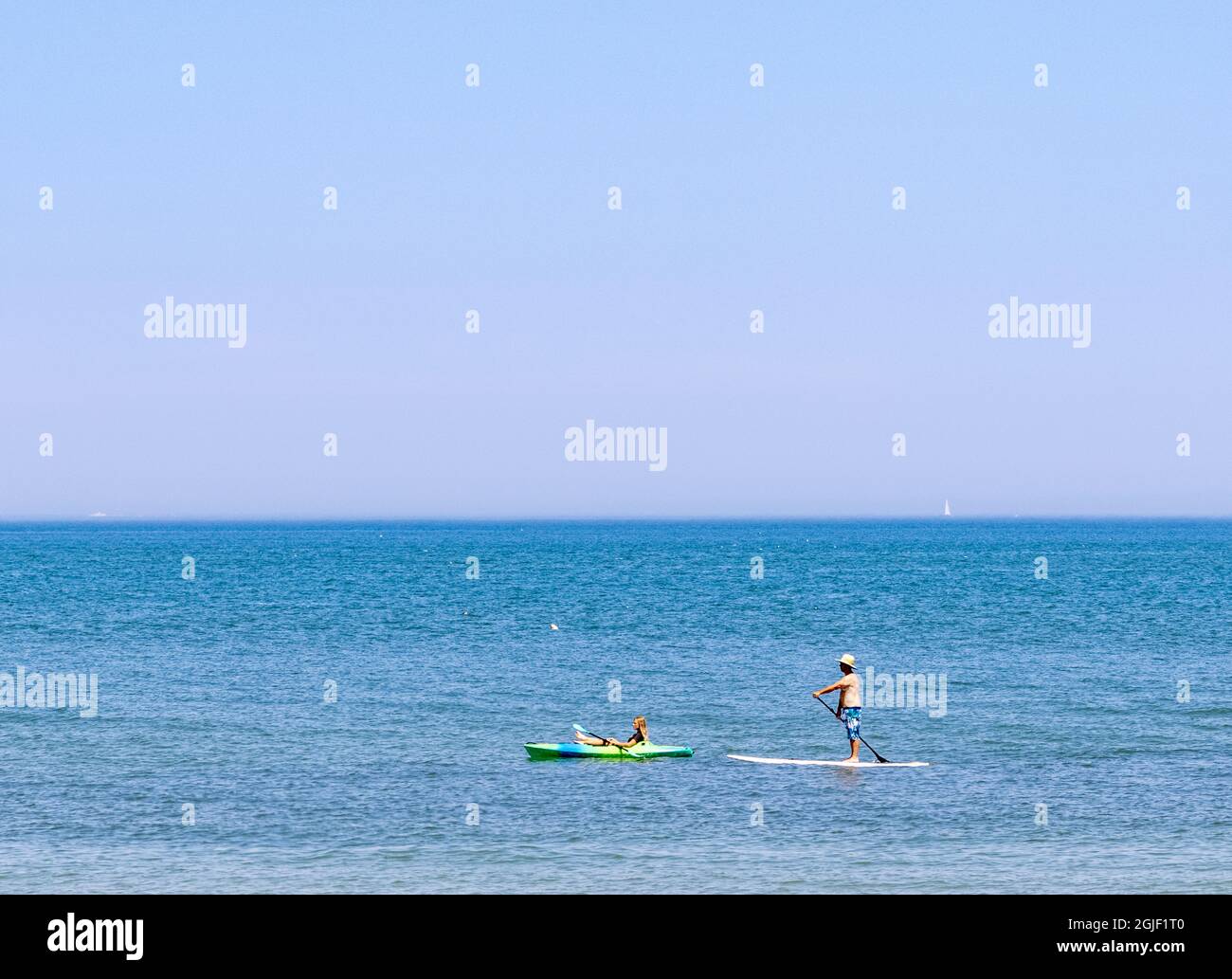 Coppia paddling boarding e kayak a Gin Beach a Montauk, NY Foto Stock