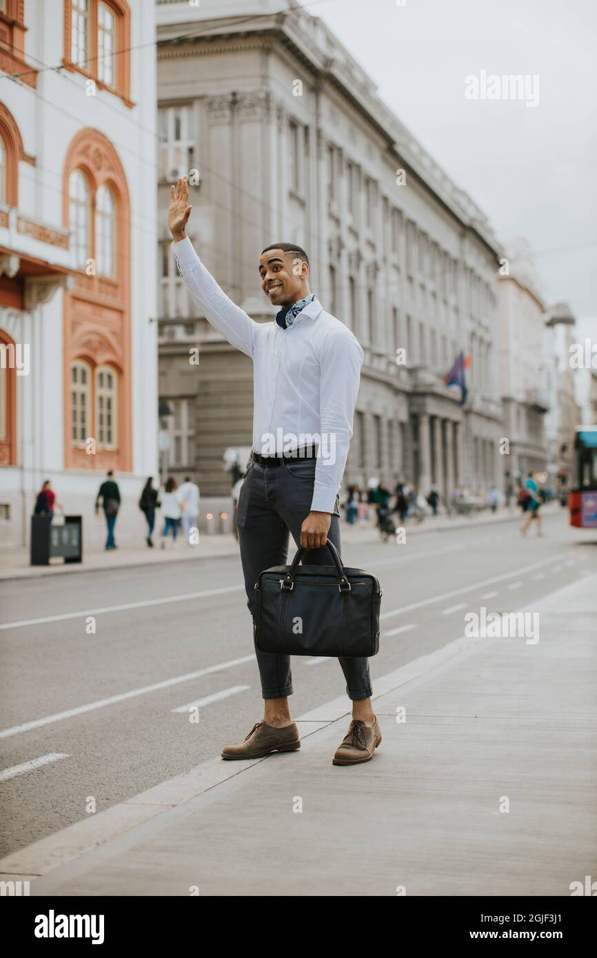Bell'uomo d'affari afro-americano che ha in attesa di un taxi su un via Foto Stock