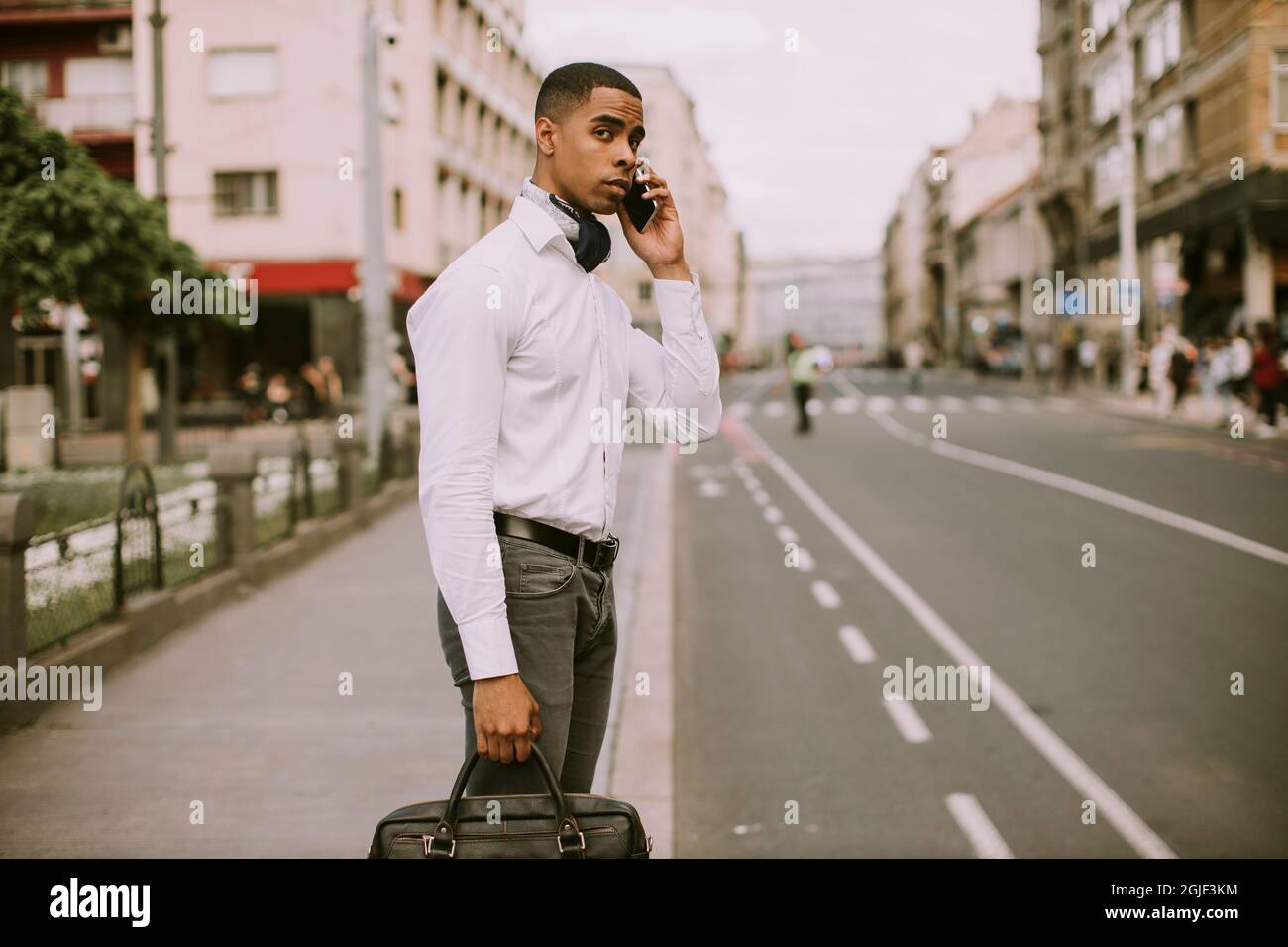 Bel giovane uomo d'affari afro-americano che usa un cellulare su una strada Foto Stock