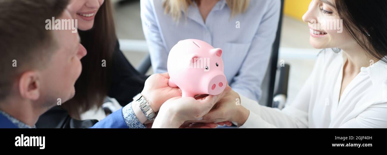 Gruppo di persone di successo affari che tengono rosa piggy banca in le loro mani in primo piano Foto Stock