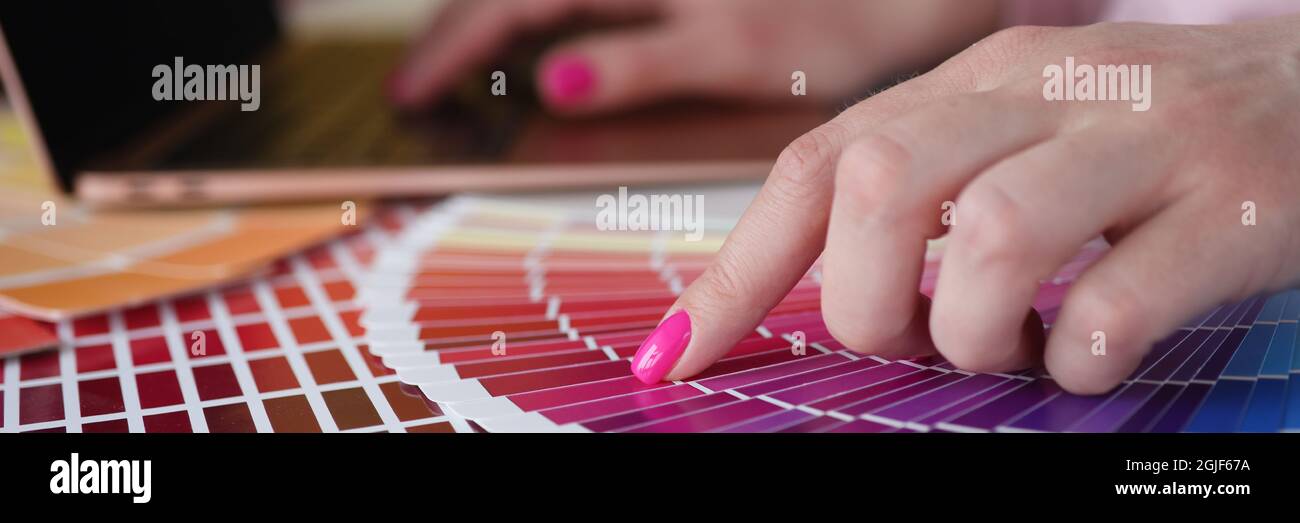 Donna con manicure rosa che mostra campioni di colore in primo piano del catalogo Foto Stock