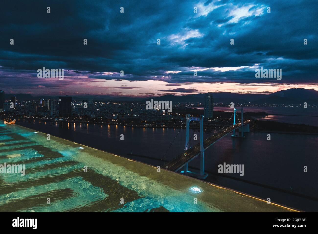 Vista notturna dalla piscina sul tetto dell'hotel all'oceano e al grande ponte della grande città. Vista pittoresca Foto Stock