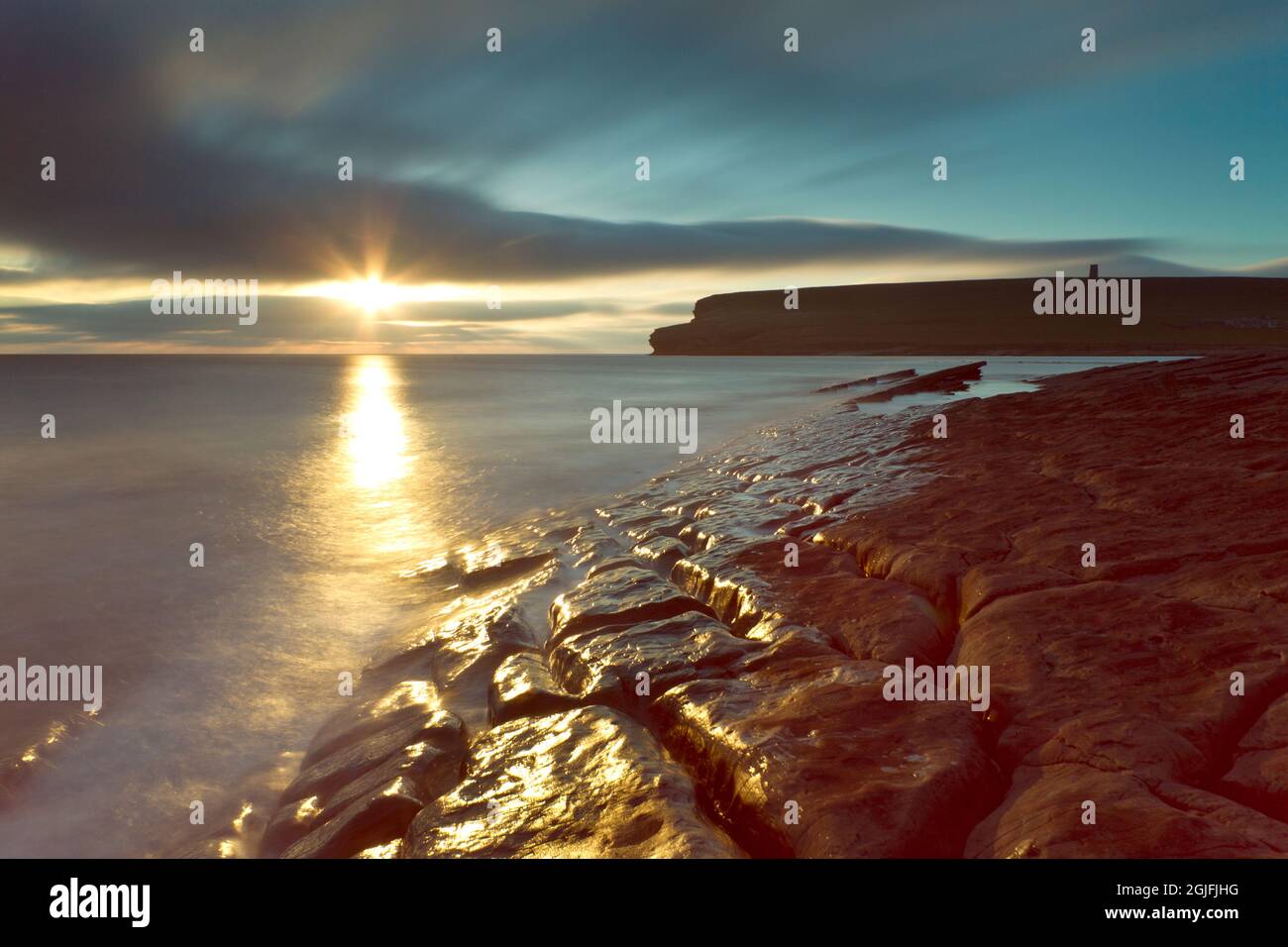 Tramonto con rocce bagnate lungo la costa di Marwick, Isole Orkney Foto Stock