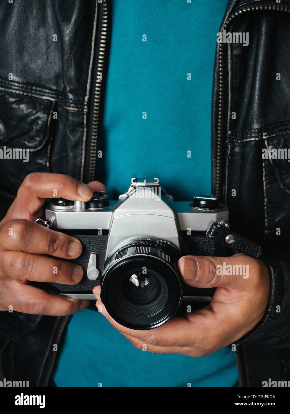 Persona etnica che indossa una giacca in pelle e che tiene una fotocamera reflex digitale d'epoca Foto Stock