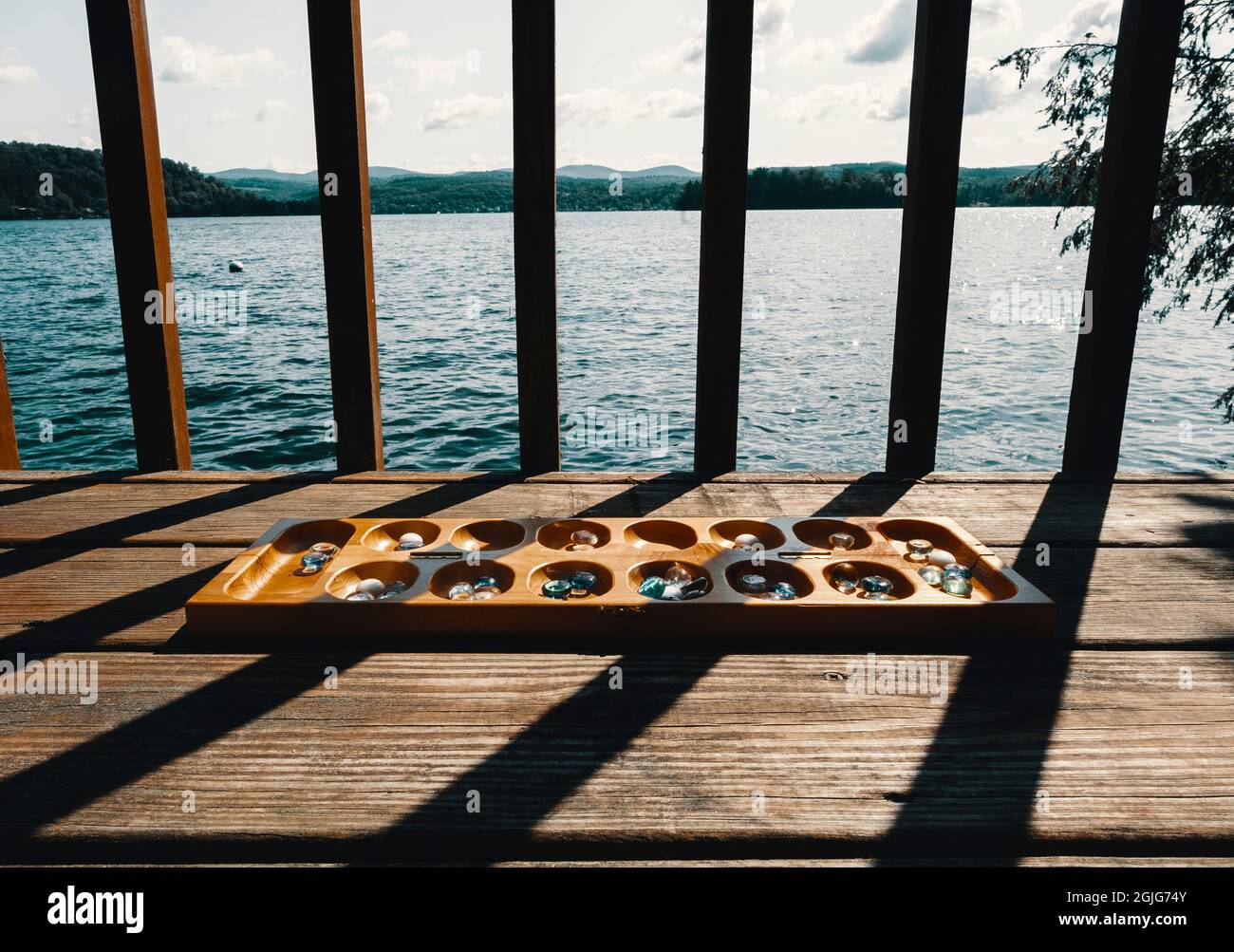 Tradizionale gioco di tavolo Mancala con pezzi di vetro e sfondo lago paesaggio Foto Stock