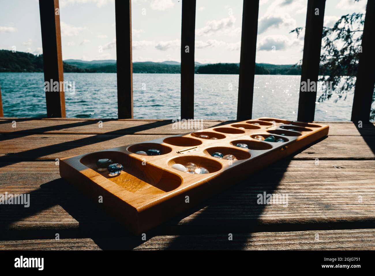 Tradizionale gioco di tavolo Mancala con pezzi di vetro e sfondo lago paesaggio Foto Stock