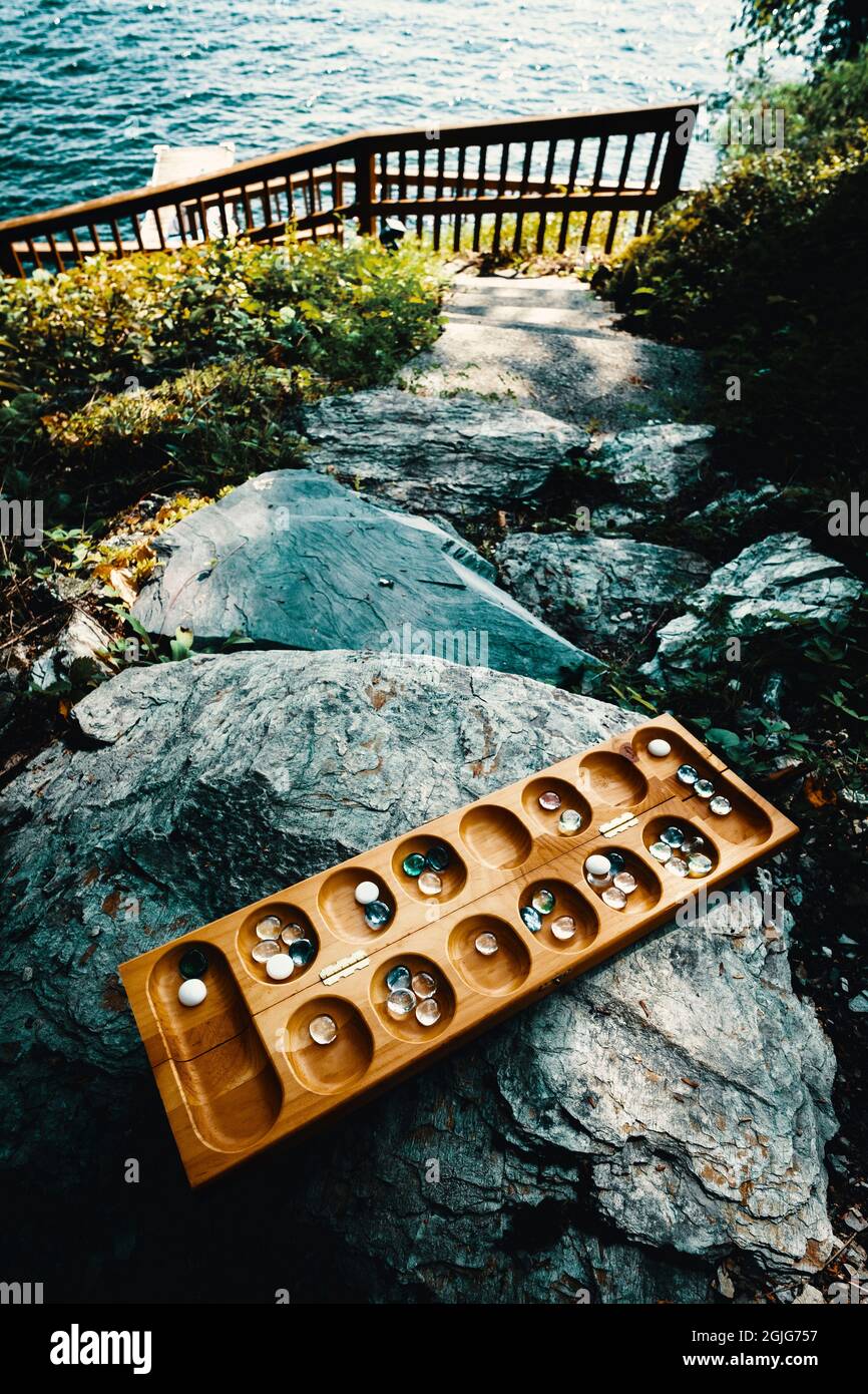 Tradizionale gioco di tavolo di Mancala con pezzi di vetro sul percorso di roccia all'esterno Foto Stock