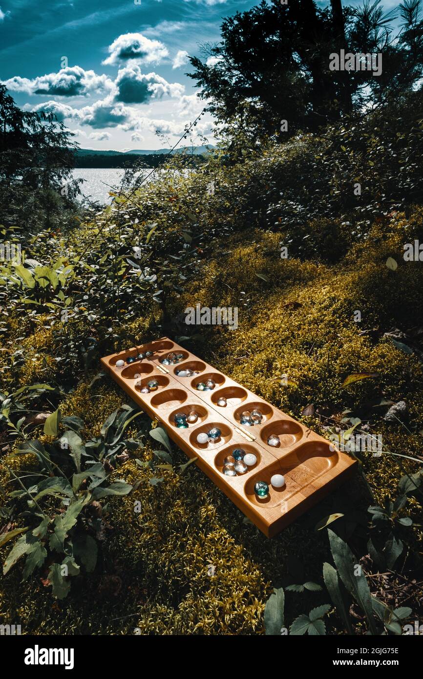Tradizionale gioco di tavolo Mancala con pezzi di vetro sul letto di muschio all'esterno Foto Stock