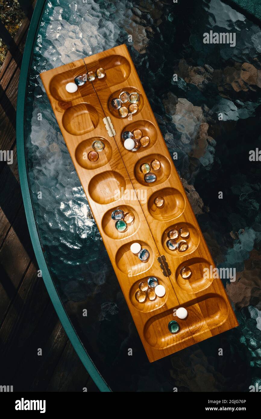 Tradizionale gioco di tavolo Mancala con pezzi di vetro su tavolo rotondo all'aperto Foto Stock