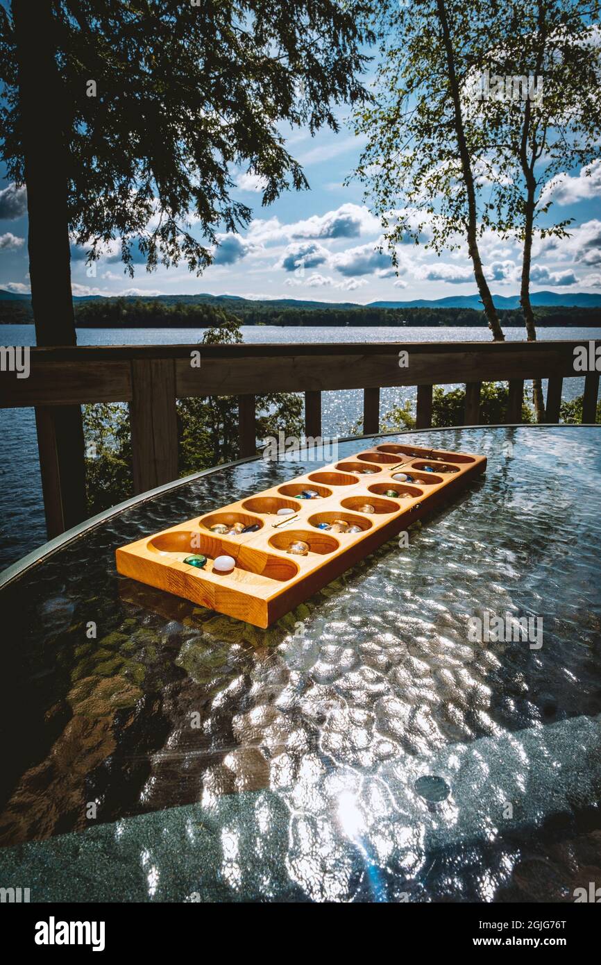 Tradizionale gioco di tavolo Mancala con pezzi di vetro con tranquillo sfondo lago Foto Stock