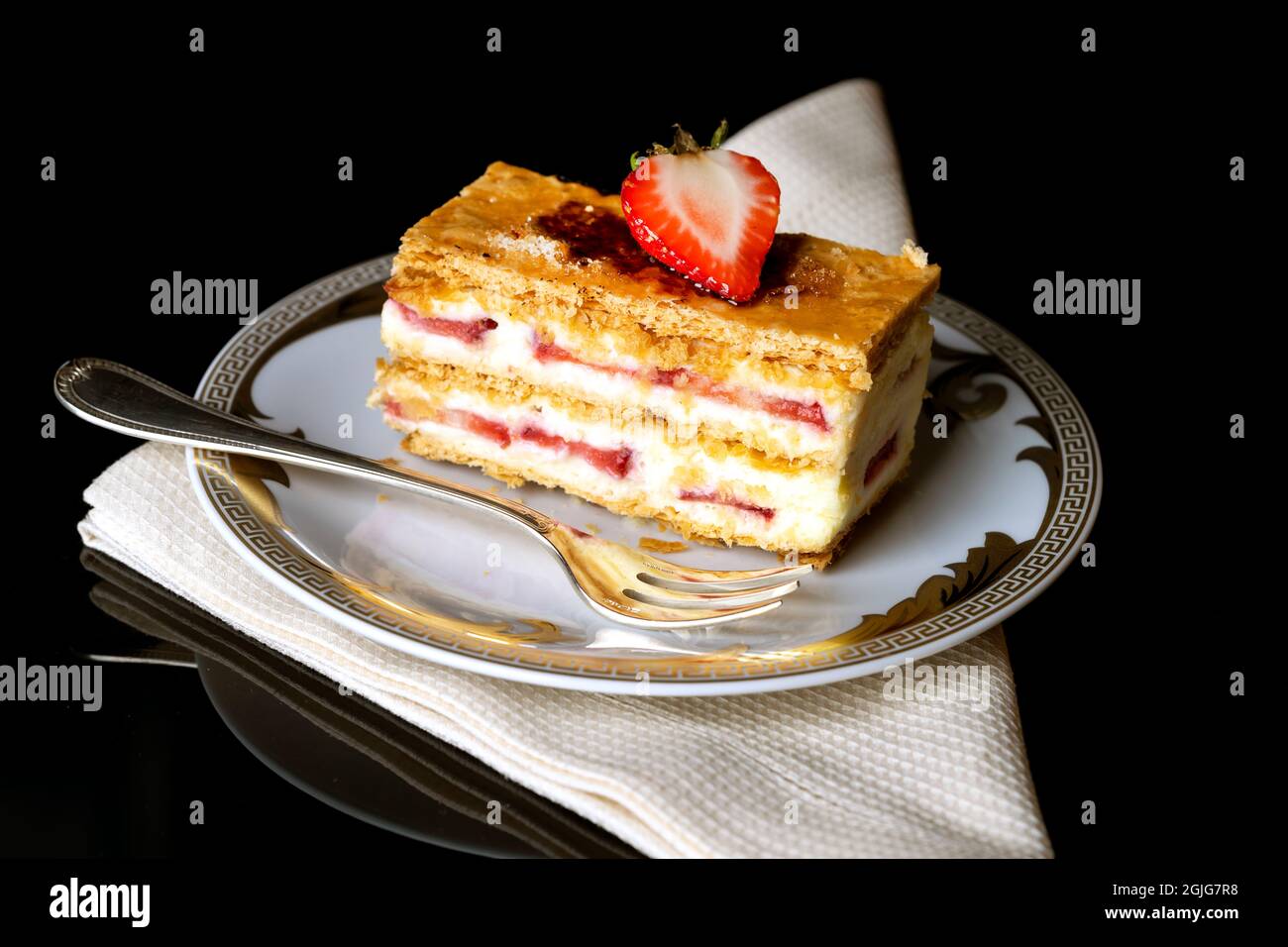 Napoleone fragola su un piatto bianco con tovagliolo beige e una forchetta d'argento Foto Stock