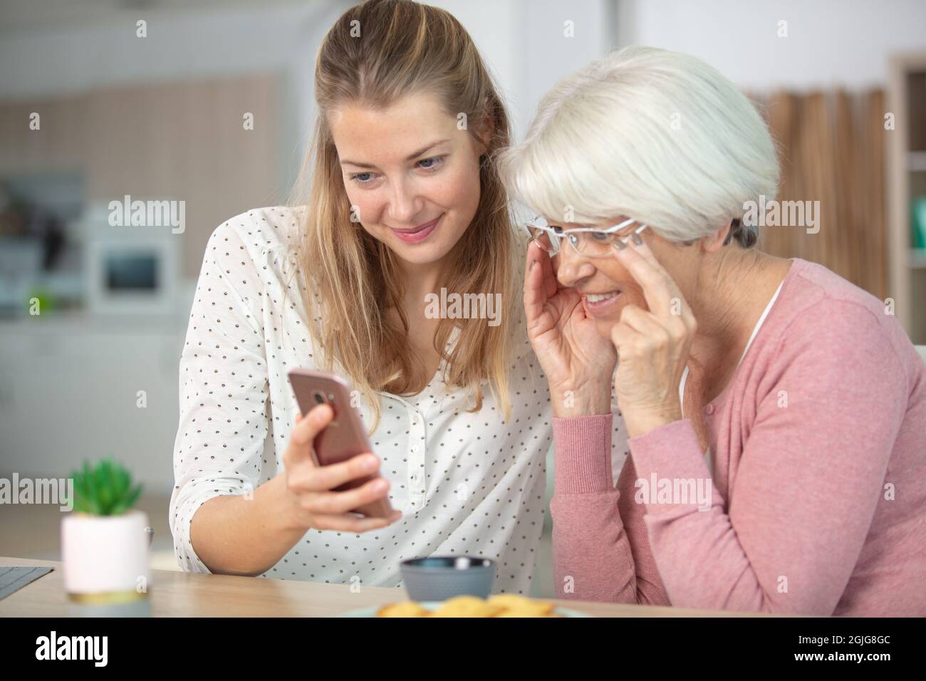 madre e figlia sorridenti e piacevoli utilizzando il telefono cellulare Foto Stock
