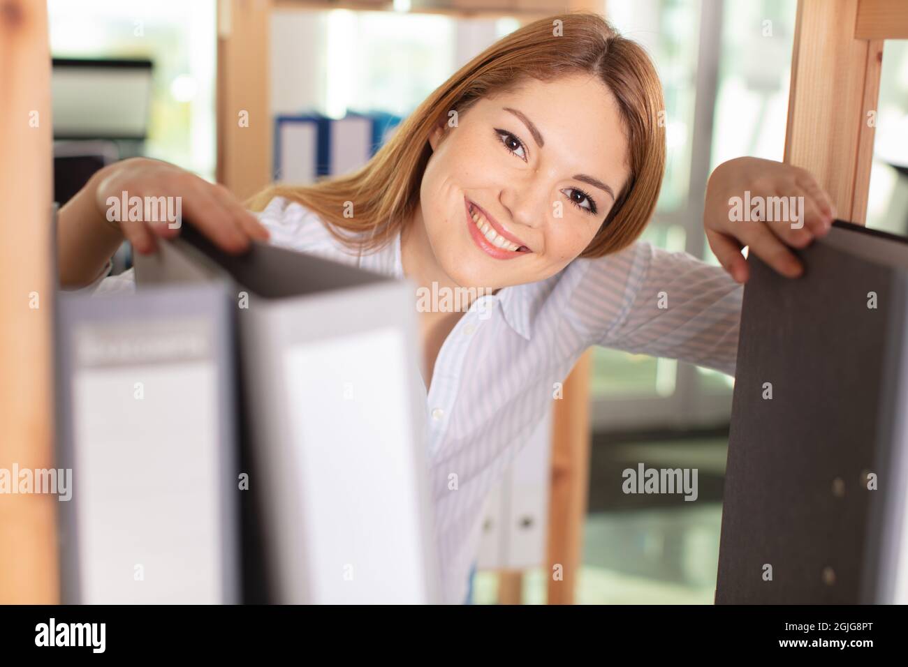 donna felice in ufficio in piedi con cartelle Foto Stock