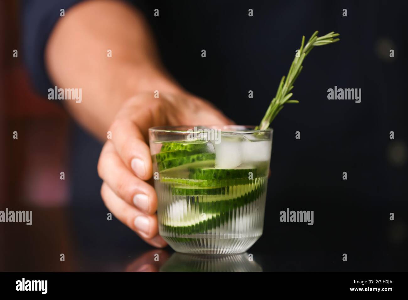 Barman maschio che tiene un bicchiere di gin cetriolo e tonico al bar Foto Stock