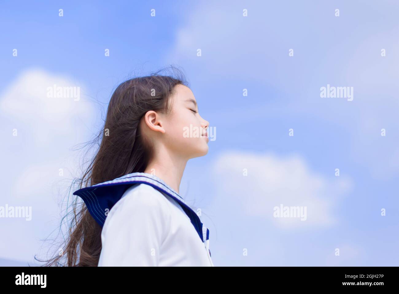 Vista laterale della studentessa che gode di brezza estiva, sorridente con gli occhi chiusi Foto Stock