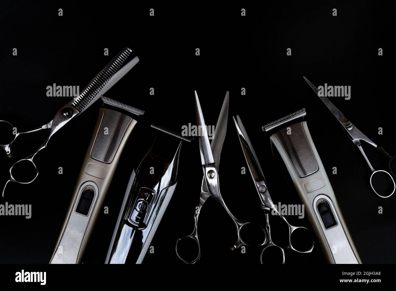 Una serie di strumenti per il taglio dei capelli su sfondo nero per il taglio di barbiere parrucchiere Foto Stock