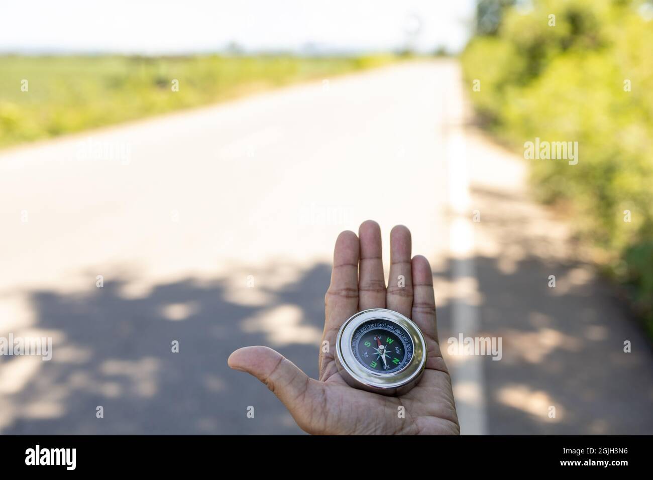 Viaggiatore maschile che tiene una bussola magnetica su strada asfaltata, orientamento e trovare il vostro modo. Foto Stock