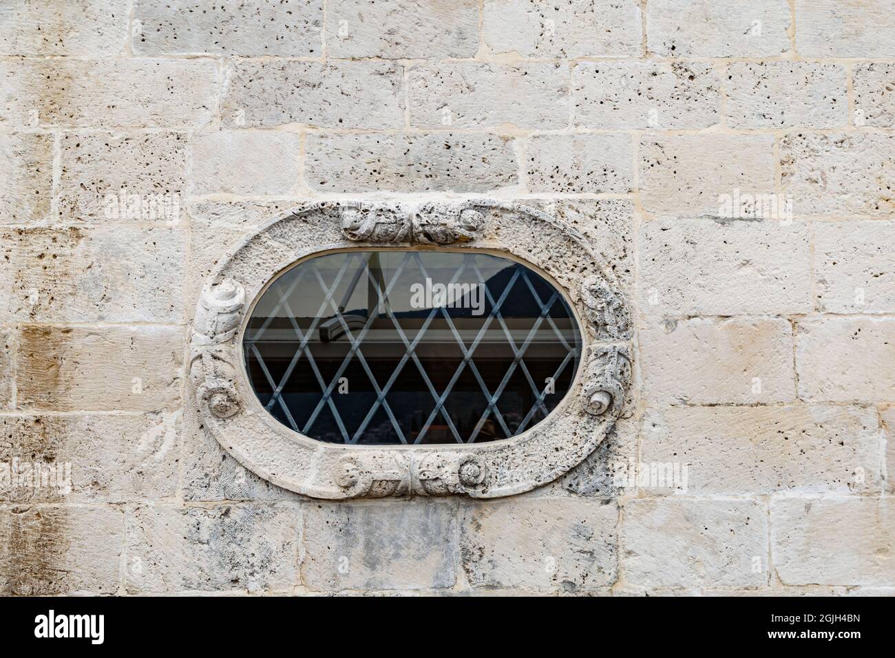 Finestra ovale buco in un vecchio edificio in mattoni con una rete  metallica su di esso Foto stock - Alamy