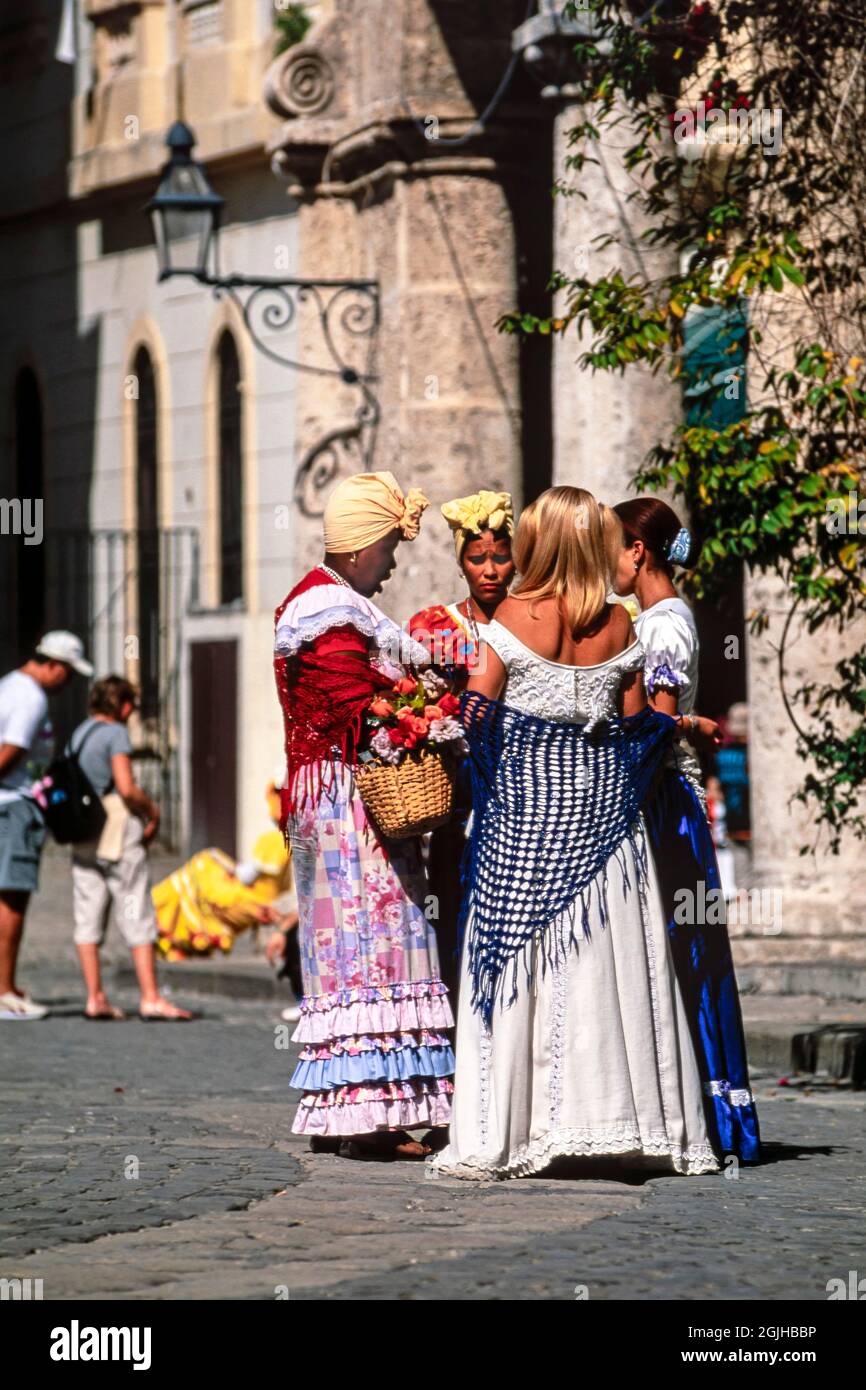 Donne cubane in abito tradizionale in attesa di posa con i turisti, Piazza della Cattedrale, l'Avana Vecchia, Cuba Foto Stock