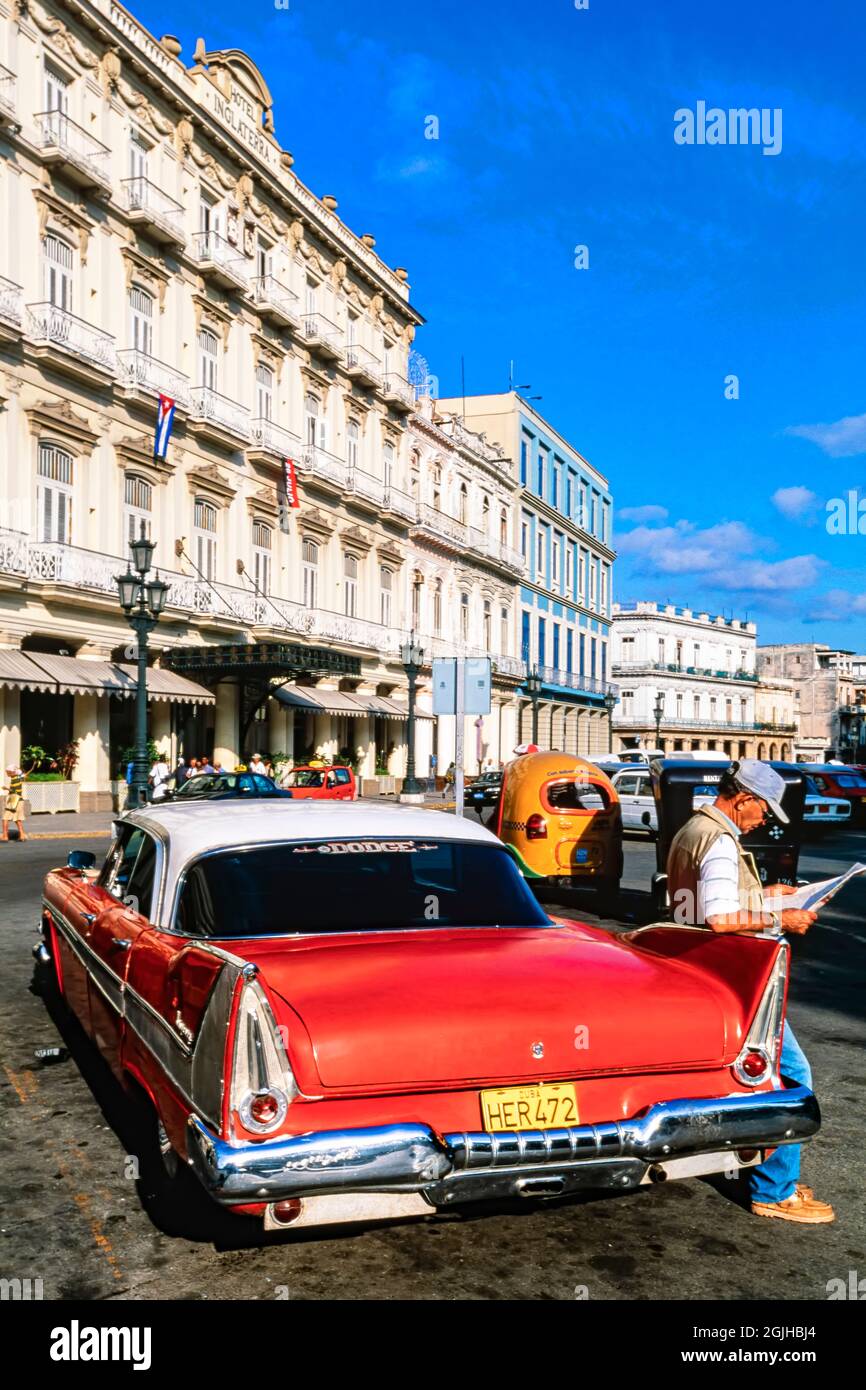 Auto classica americana anni '50, 1958 Dodge Kingsway, parcheggiata fuori dall'Hotel Inglaterra, con autista che legge il giornale, l'Avana, Cuba Foto Stock