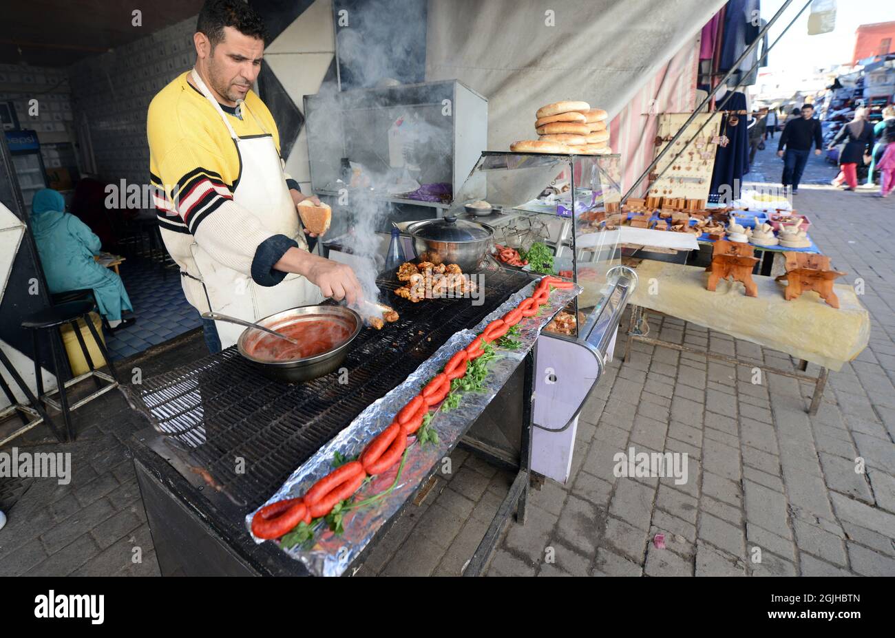 Un uomo marocchino che grigliava carne e sauseges marocchini tradizionali in un piccolo ristorante nella medina di Salé, Marocco. Foto Stock