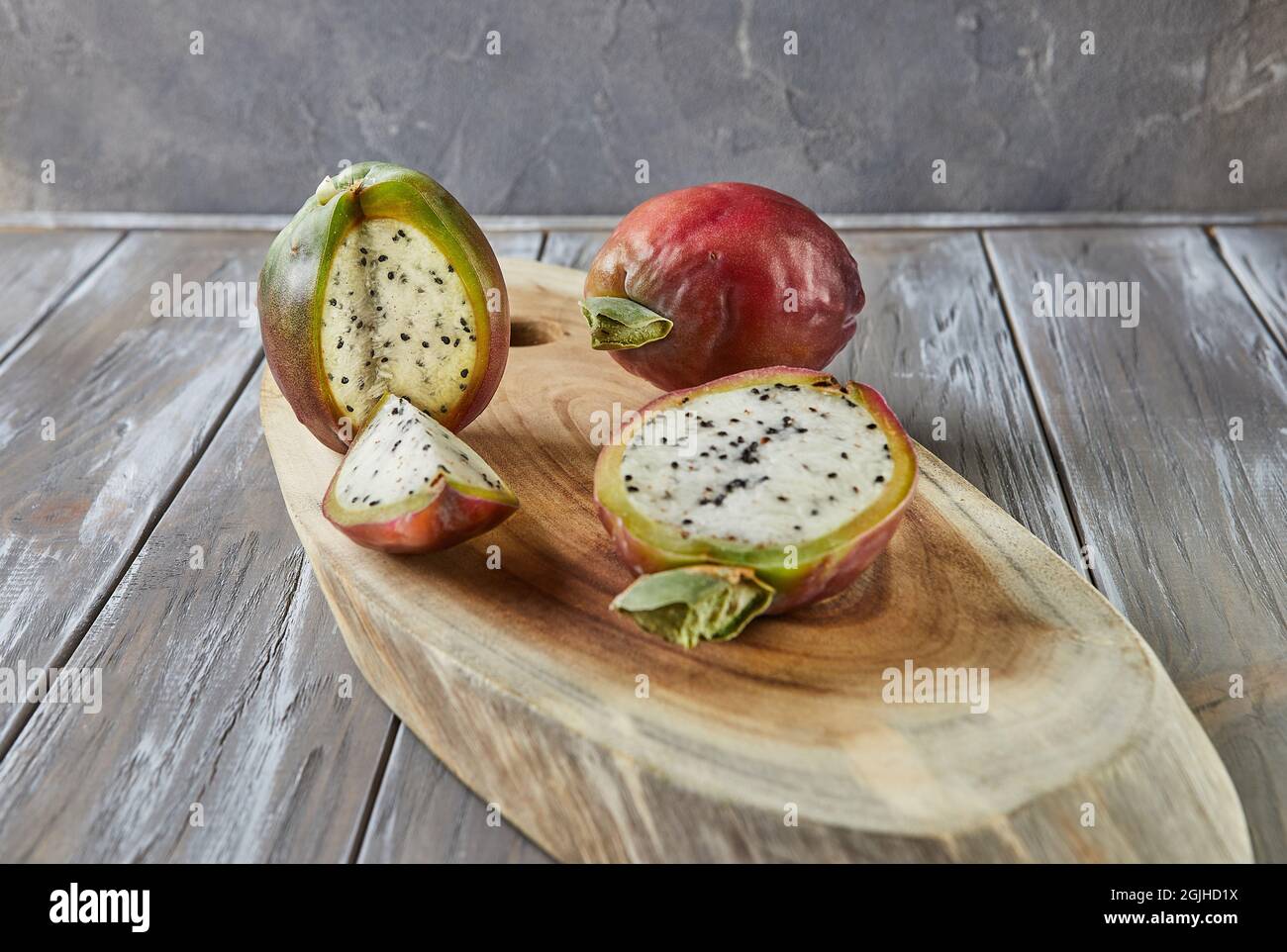 Frutta di cactus di mela peruviana intera e tagliata su supporto di legno su tavola grigia. Nome scientifico Cereus repandus. Foto Stock