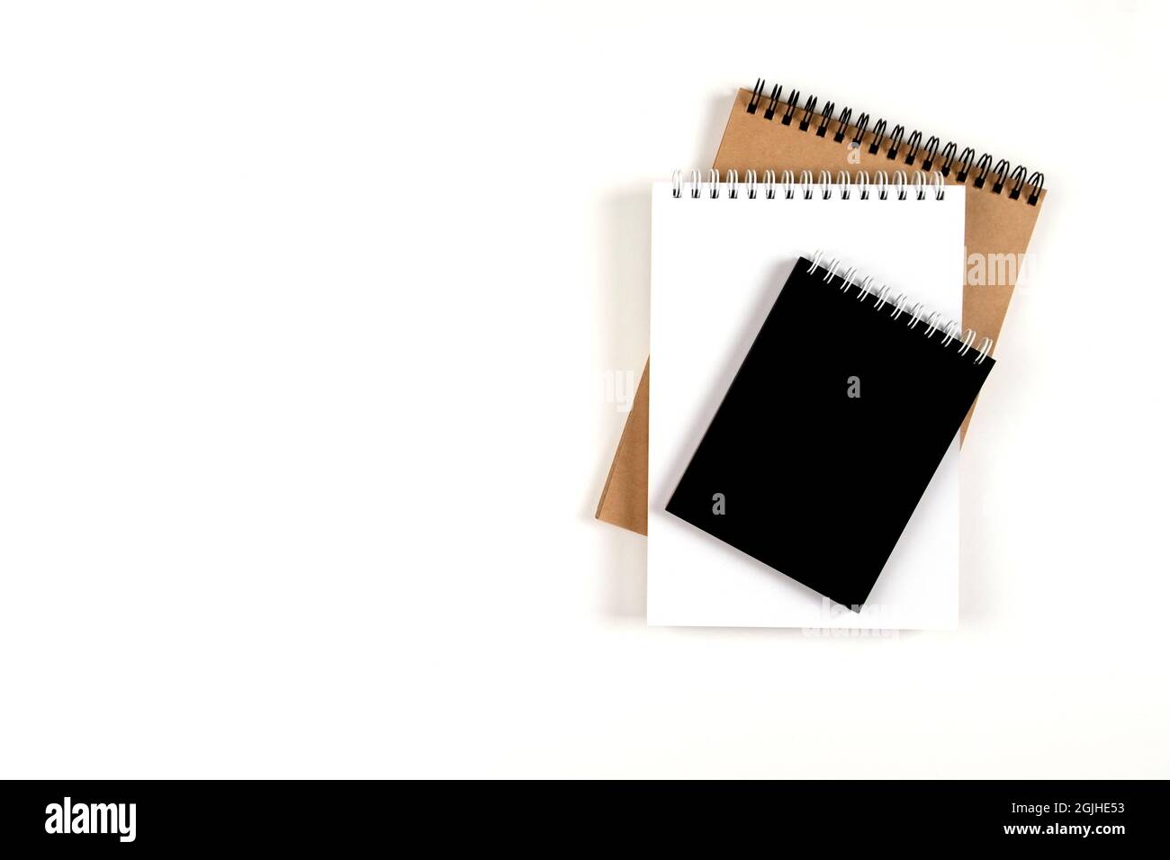 Tre blocchi note vuoti su una spirale impilati in una pila su uno sfondo bianco. Notebook con fogli bianchi, neri e riciclati. Istruzione, ufficio. Foto Stock