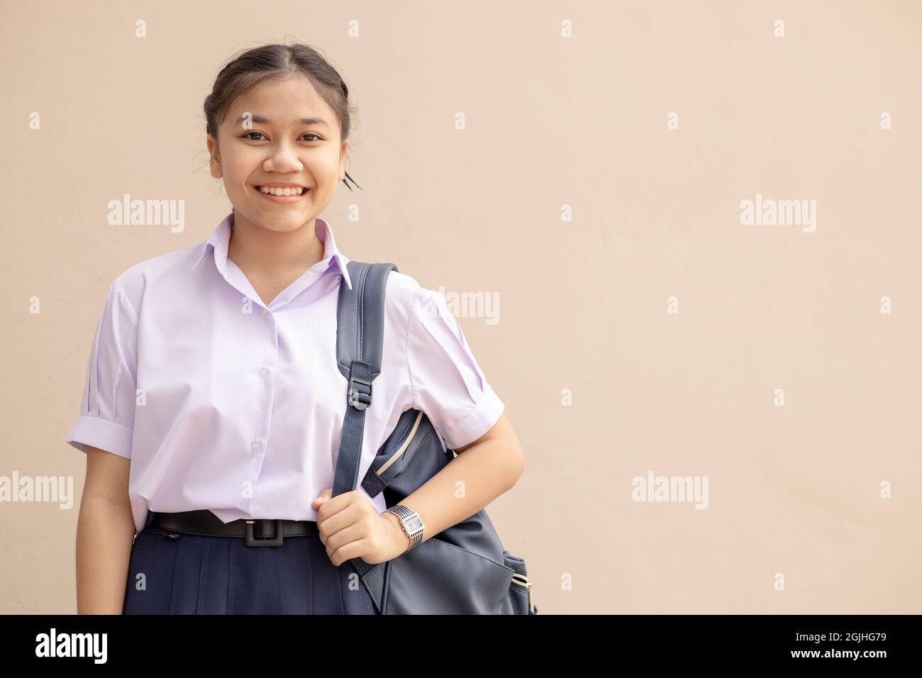 Asian School ragazza giovane studente carino in uniforme sorriso felice con borsa guardando fotocamera con spazio per il testo. Foto Stock
