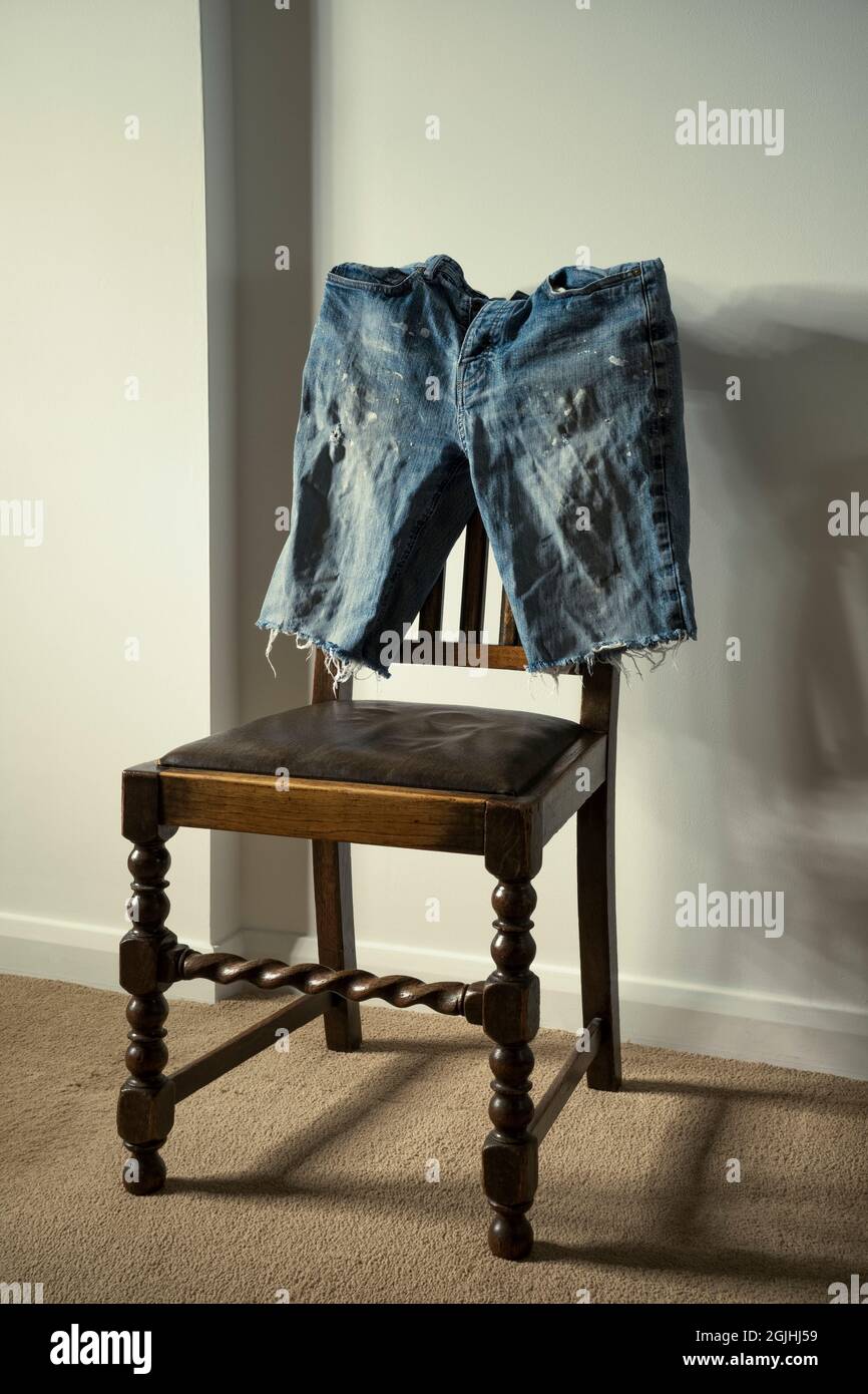 Vecchi pantaloncini in denim su una sedia di legno. Foto Stock