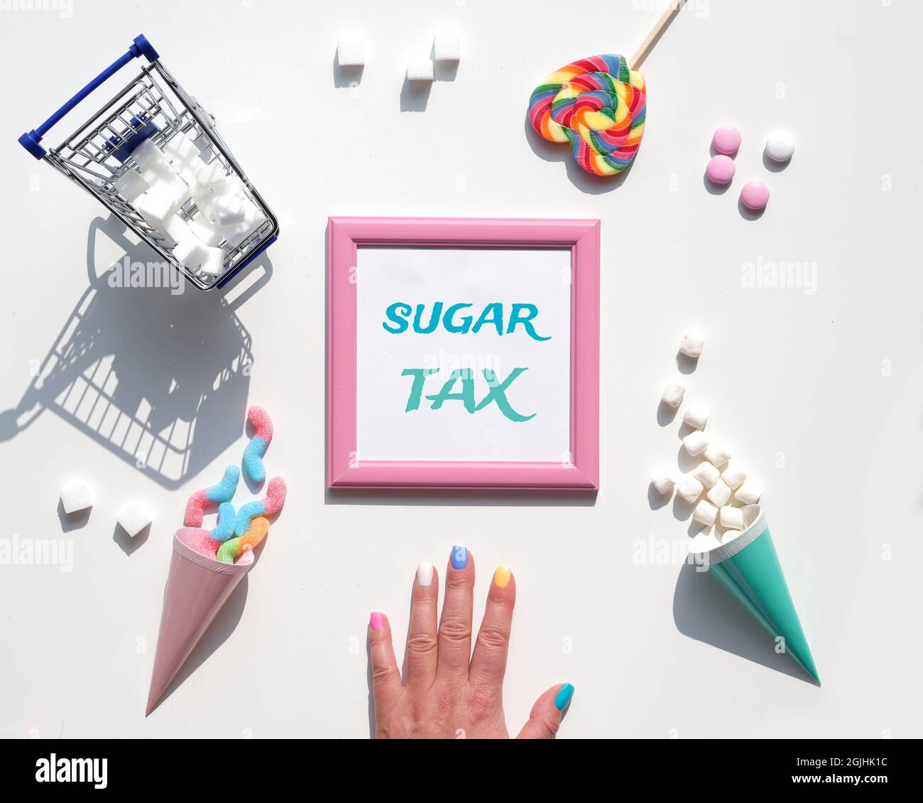 Texte sur Sugar Tax. Vari snack gustosi in colori pastello, rosa, verde menta, su sfondo bianco. Eccesso di dolci, cioccolato, caramelle, dolci. Concetto Foto Stock