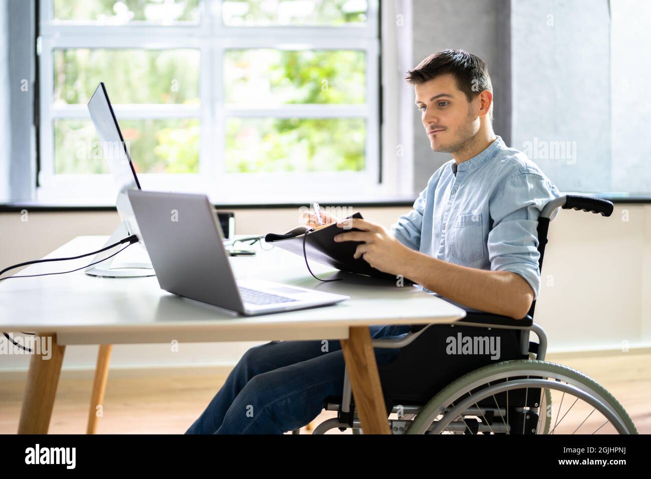 Assistente virtuale disabilitato in sedia a rotelle effettua videochiamata remota Foto Stock