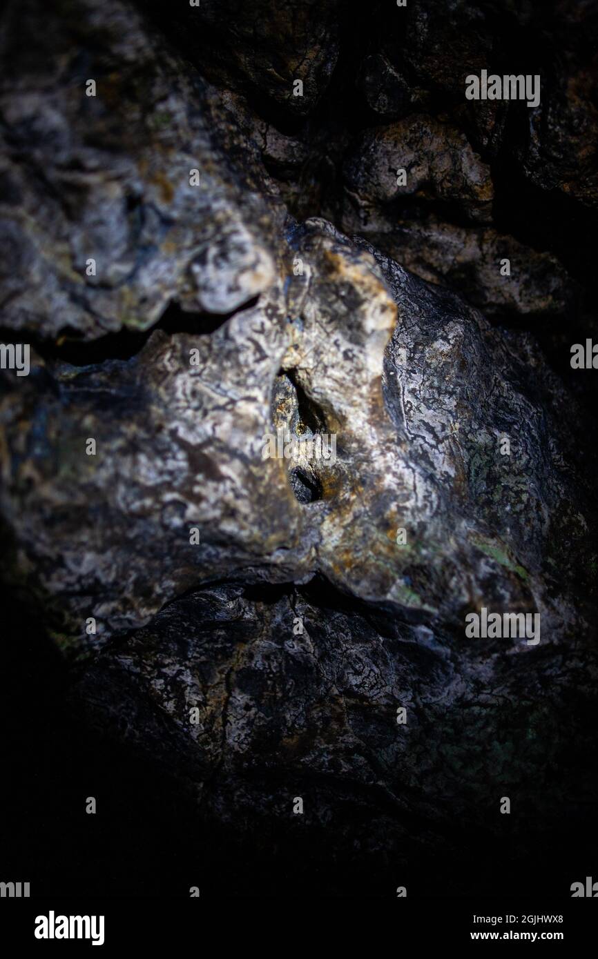 Macro foto di roccia minerale in una grotta profonda e scura | primo piano foto di rocce in una grotta nera illuminata da una torcia Foto Stock