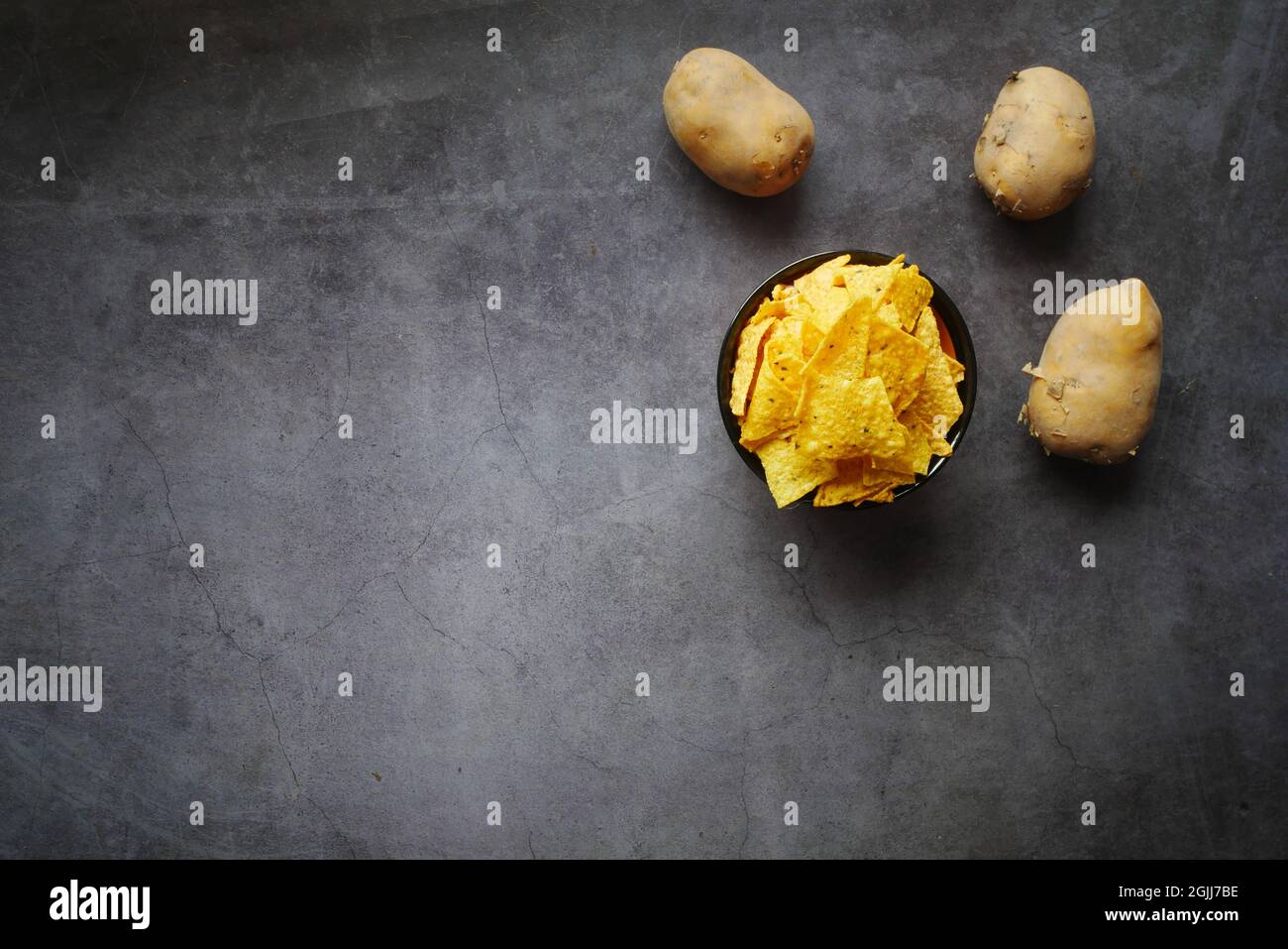 Ciotola con gustose patatine e patate su sfondo nero Foto Stock