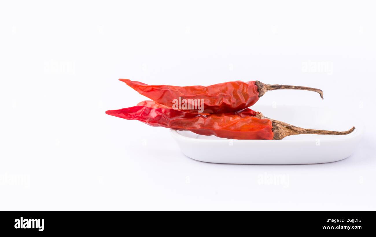 peperoncini rossi secchi o cayenne su un vassoio bianco, primo piano di spezia calda isolato su sfondo bianco Foto Stock