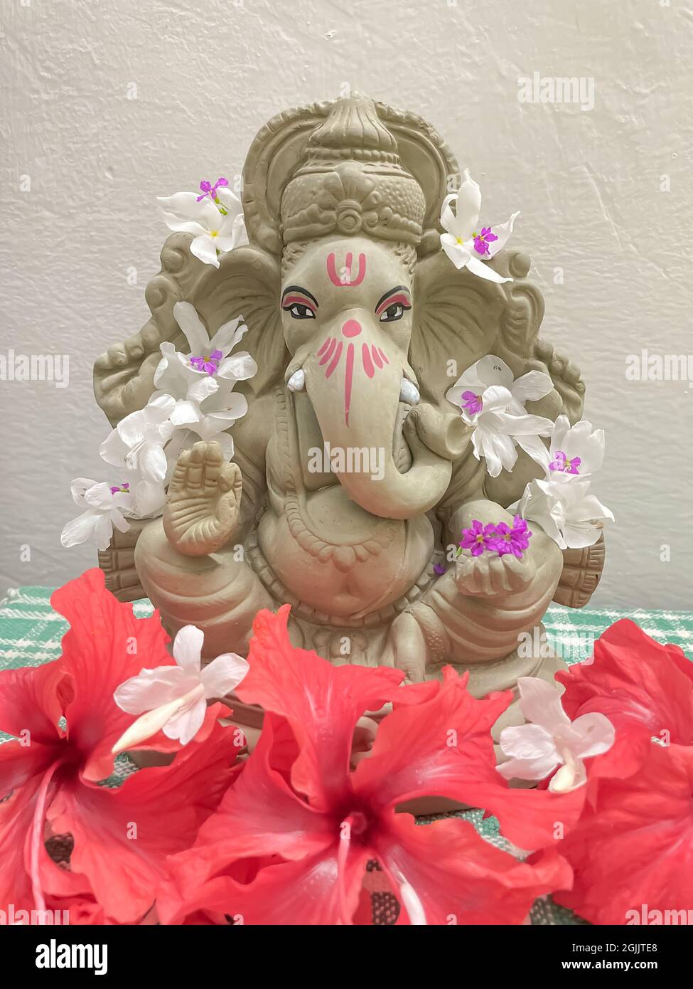 Lord Ganesh idol fatto di fango e decorato con fiori bianchi e rossi Foto Stock