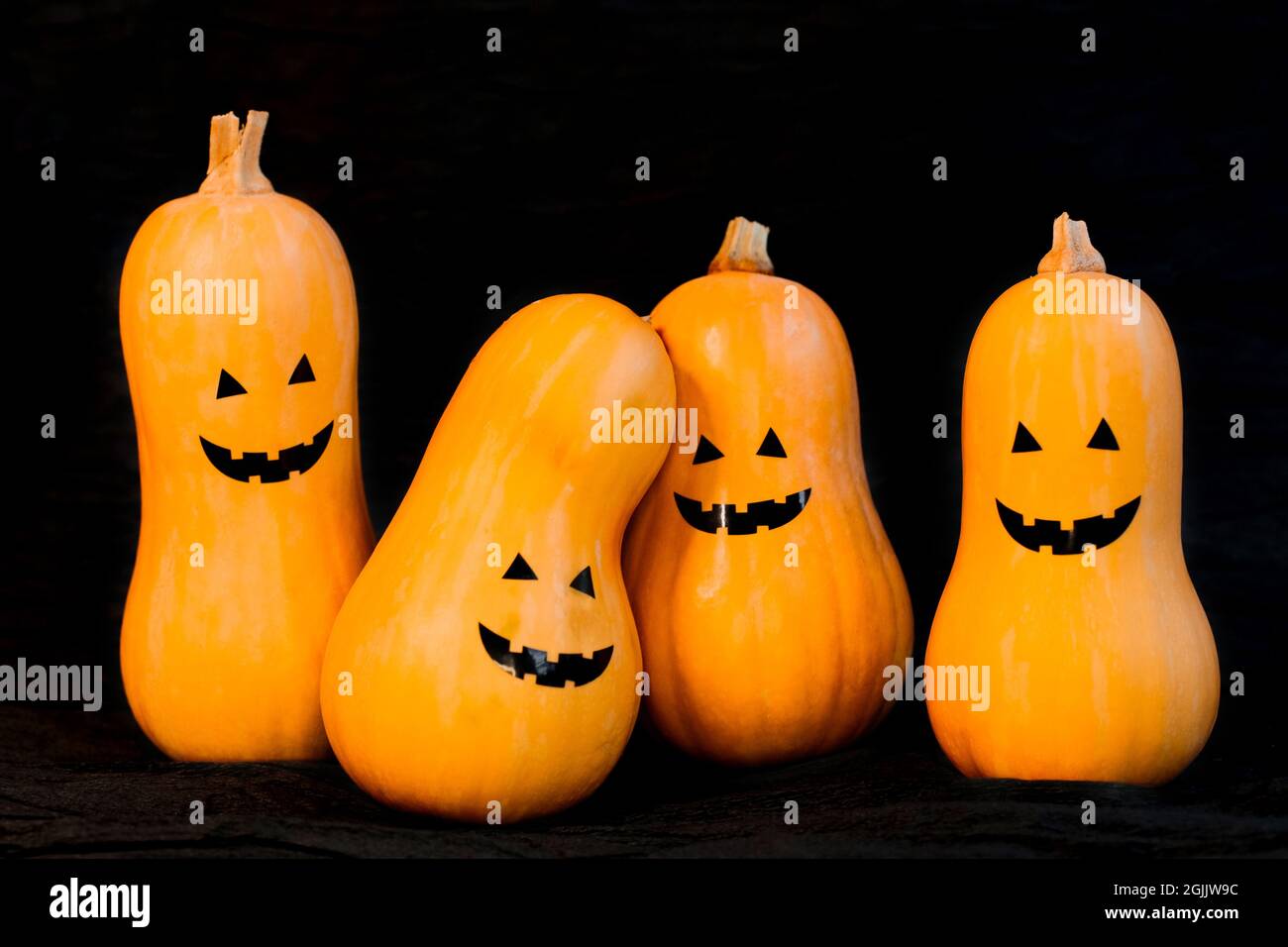 Quattro zucche con le facce insidiose allegre su Halloween su uno sfondo nero, copyspace. Foto di alta qualità Foto Stock