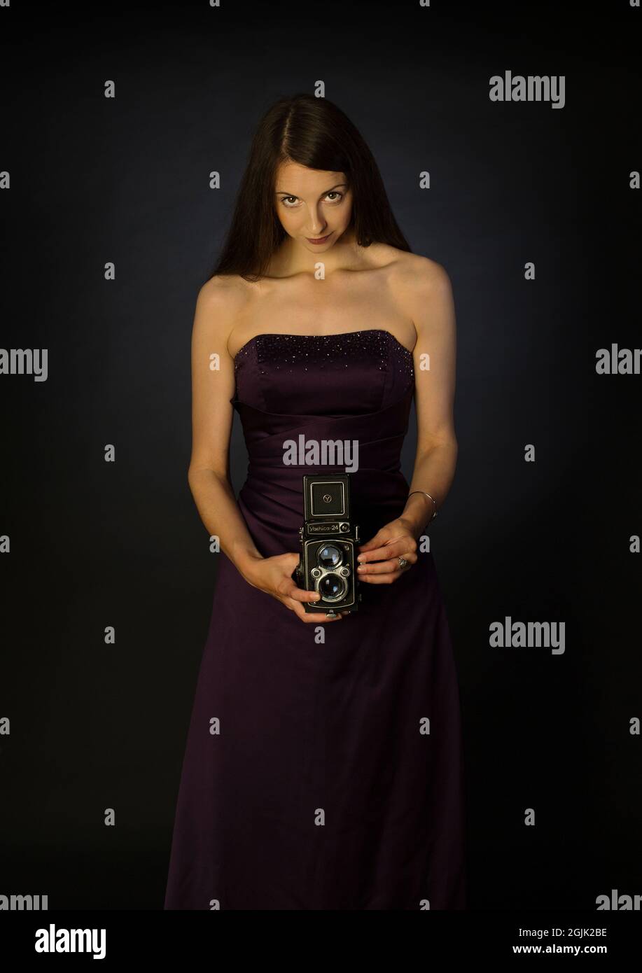 Una bella fotografa femminile in un abito lungo utilizzando una fotocamera di formato medio Foto Stock