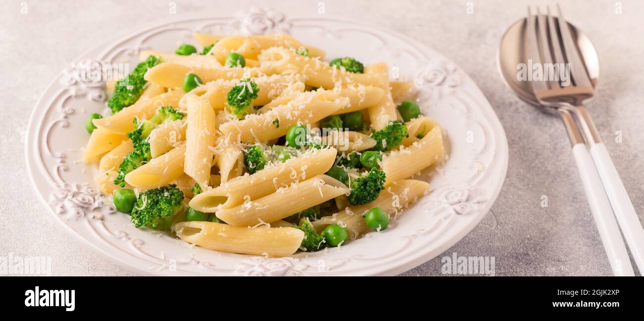 Pasta con piselli verdi, broccoli e parmigiano su sfondo chiaro. Foto Stock