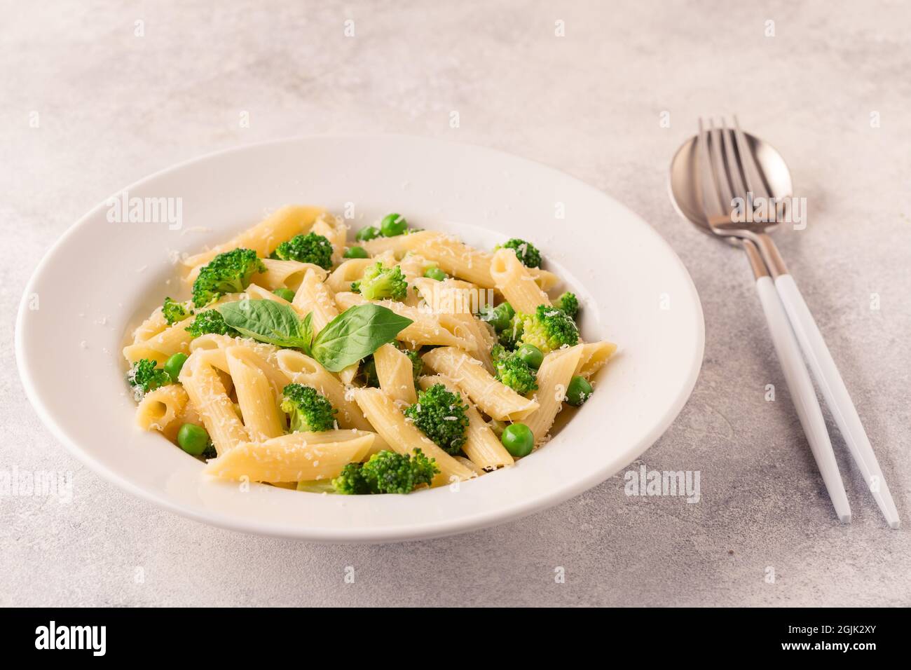 Pasta con piselli verdi, broccoli e parmigiano su sfondo chiaro. Foto Stock